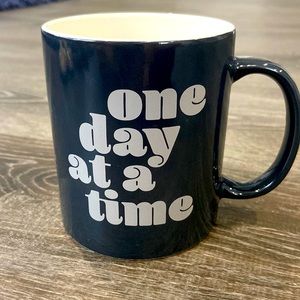 Black mug, “One day at a time” inspirational message.